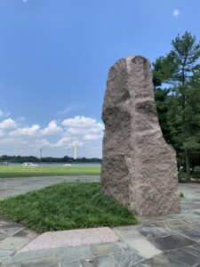 A pink granite slab in the middle of a circle, with a large obelisk, the Washington monument, in the distance.