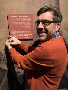 A man places a vinyl wrapper over a museum display sign.