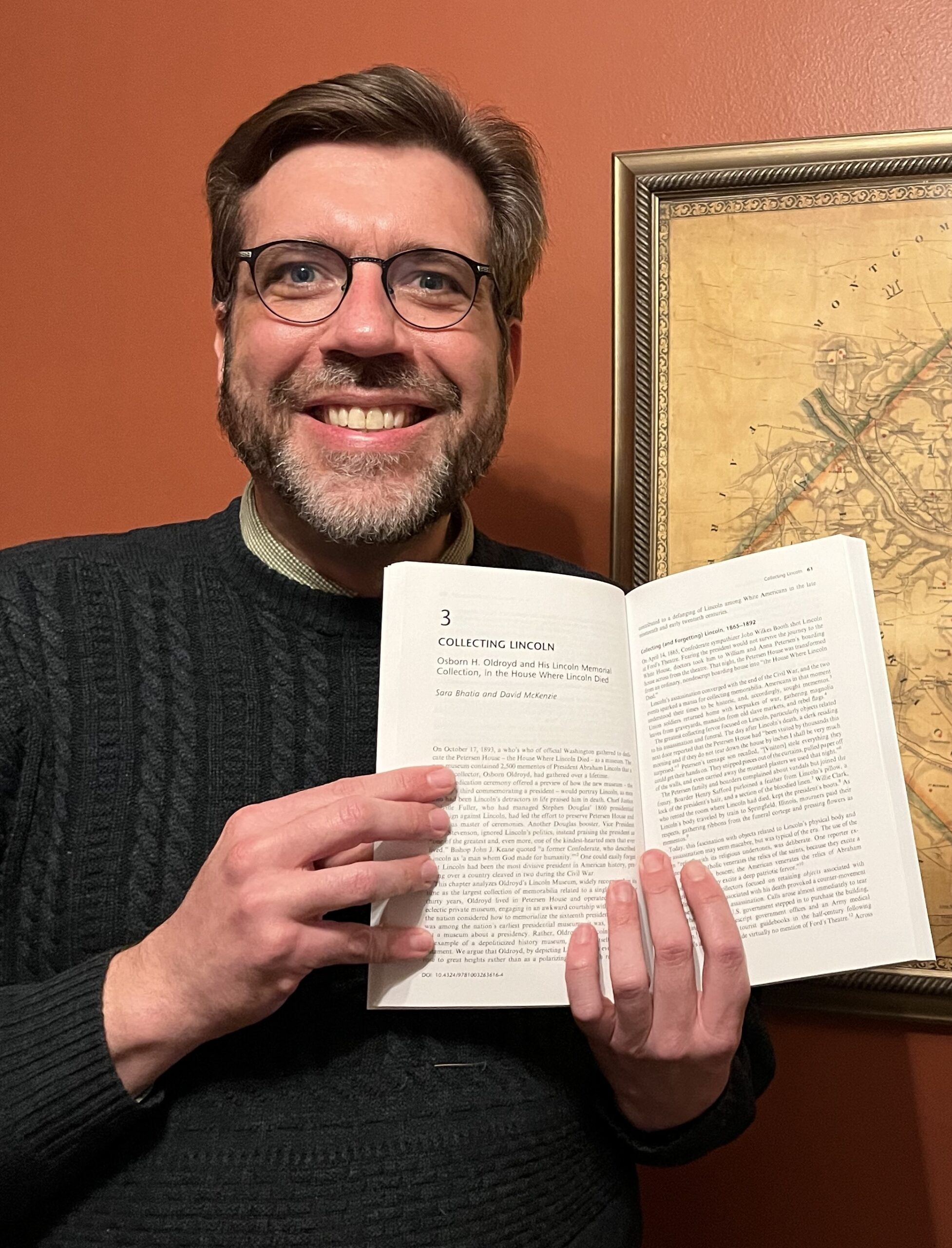 A man holding a book open to a chapter called "Collecting Lincoln."