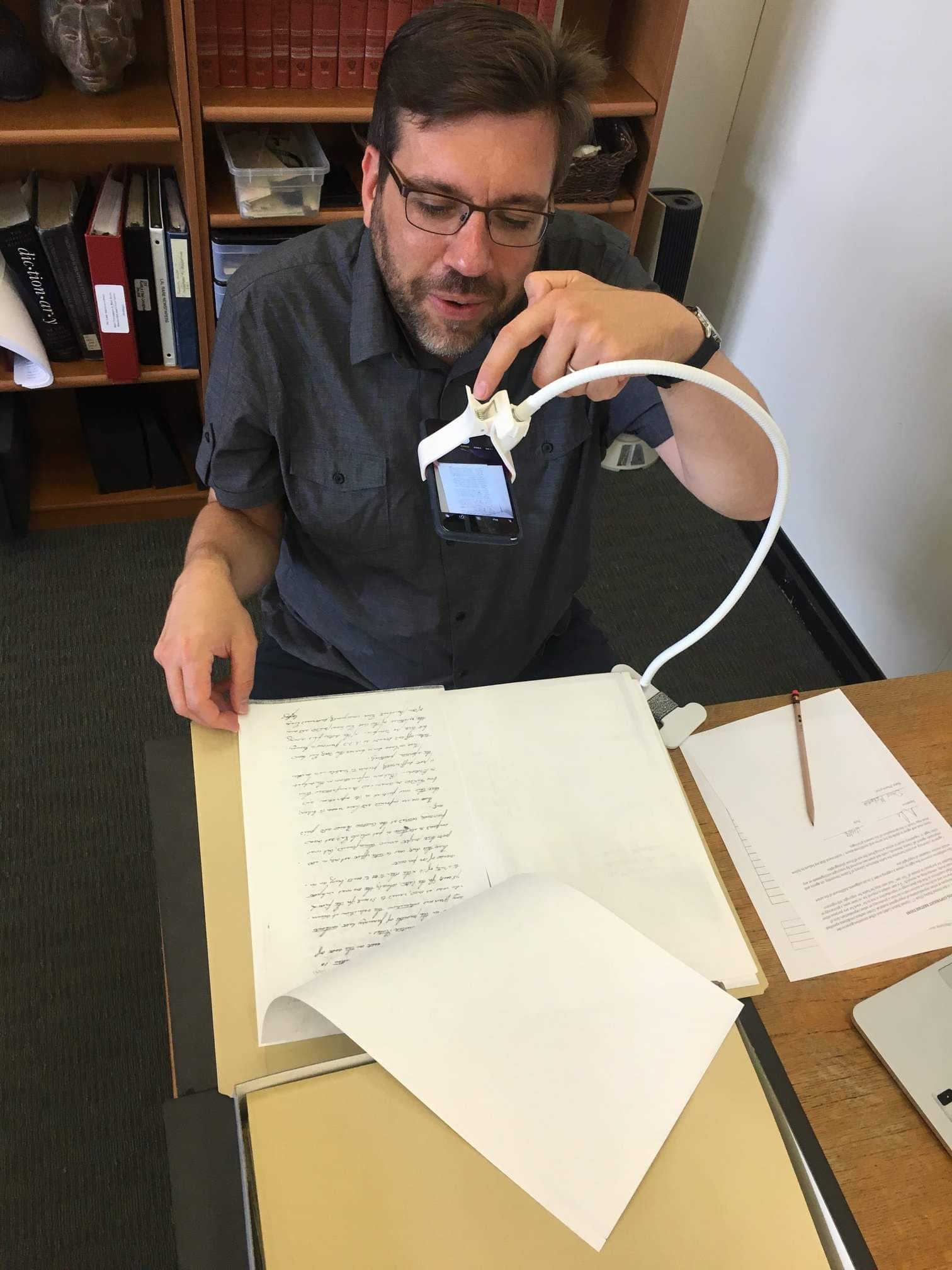 A man taking a photo of a historical document using a phone camera.