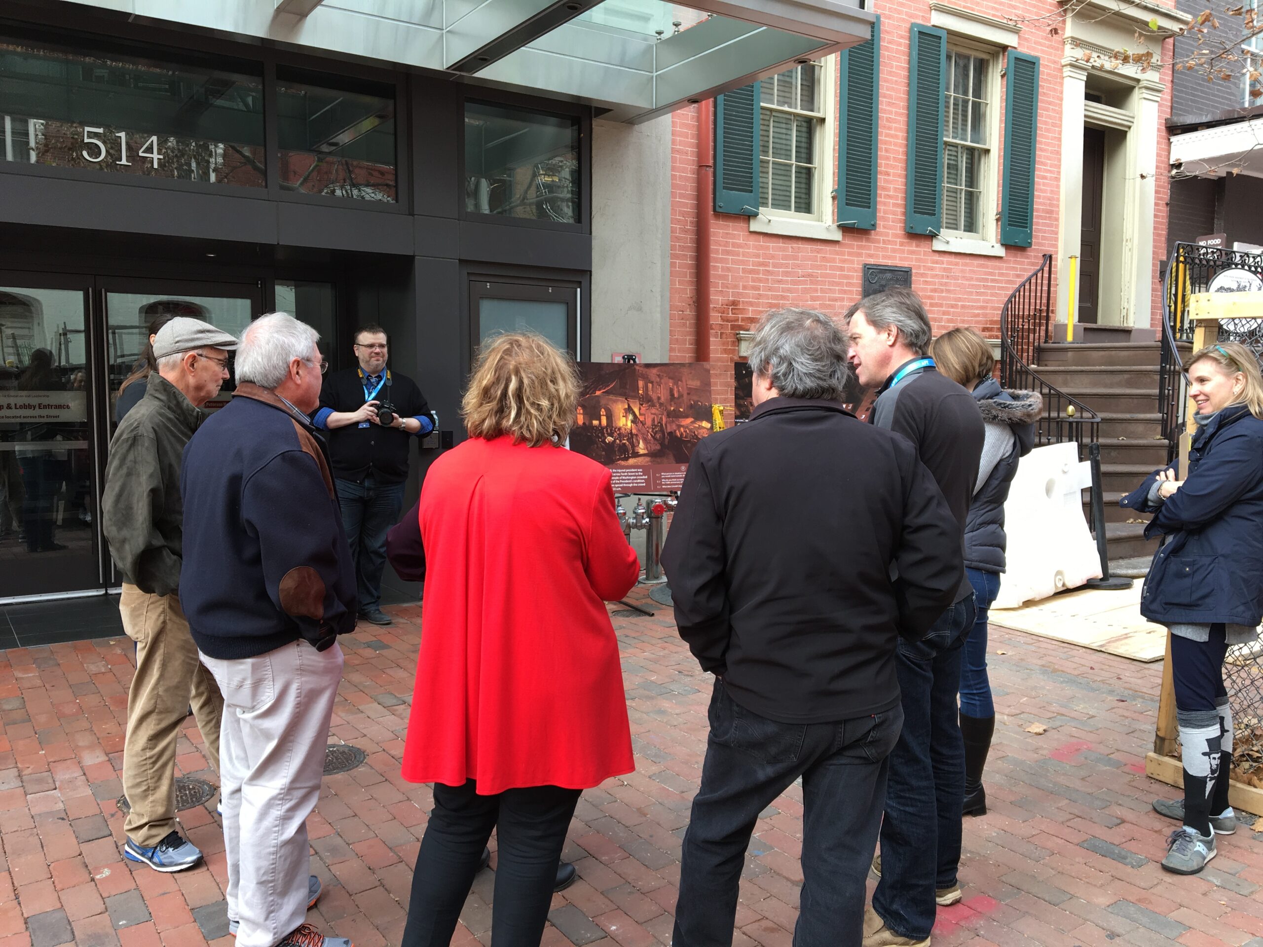 A group of people discuss an interpretive sign on an easel.