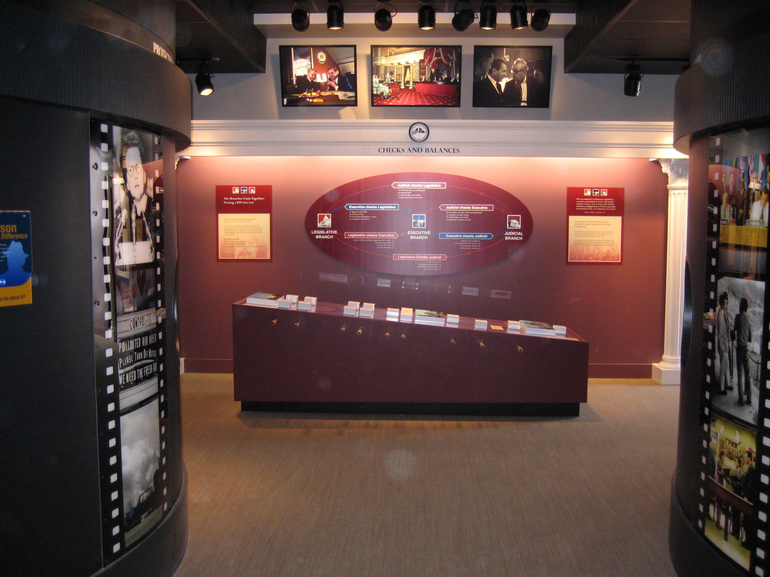 A museum exhibition featuring large photographs, graphic panels, and an interactive table.